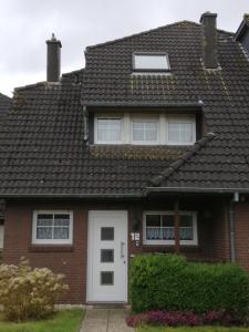 a red brick house with a white door at Ferienhaus 1260 in Tossens in Butjadingen OT Tossens