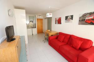 a living room with a red couch and a kitchen at DIFFERENTFLATS Aquario in La Pineda