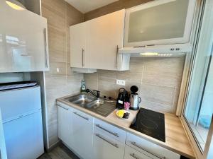 a small kitchen with white cabinets and a sink at Palm Paradise, by Welcome to Cannes in Cannes
