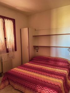 a small bedroom with a bed with a striped blanket at VILLAGGIO ANDORA COLOMBO in Marina dʼAndora