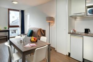 a kitchen and dining room with a table and chairs at Ténéo Apparthôtel Bordeaux Maritime - Cité du vin in Bordeaux
