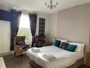 a bedroom with a bed and a chair and a window at Turks Head Rothbury in Rothbury