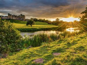 um pôr-do-sol sobre um rio com um castelo ao fundo em 1 Bed in Rothbury 88286 em Rothbury