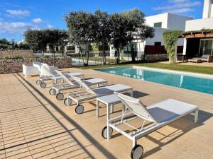 a row of lounge chairs next to a swimming pool at Villa con piscina privada y AC in Sant Lluis