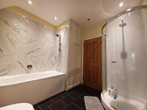 a bathroom with a tub and a shower and a toilet at The Gemstone Manor in Watford