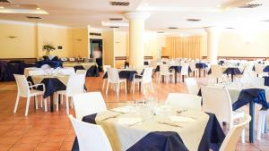 une salle de banquet avec des tables blanches et des chaises blanches dans l'établissement Villaggio Porto Rhoca, à Squillace