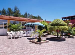 un patio con tavoli e sedie bianchi e ombrelloni di HOTEL IL SILLABARIO a Iglesias