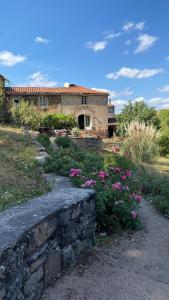 a house with a stone wall and some flowers at La Grande Combe in Saint-Izaire