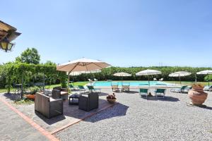 un patio con sedie e ombrelloni accanto alla piscina di Agriturismo Villa La Morina a Cortona