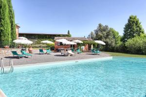 una grande piscina con sedie e ombrelloni di Agriturismo Villa La Morina a Cortona