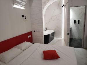 a bedroom with a white bed with a red pillow on it at Red & Yellow Old Town in Lviv +3 photos