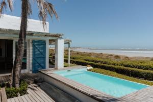a house with a swimming pool next to the beach at Djis Tjil in Paternoster
