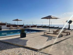 a swimming pool with two chairs and an umbrella at The Ocean / Ericeirahills in Carvoeira