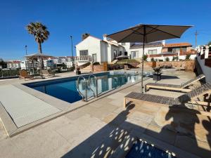 a swimming pool with two chairs and an umbrella at The Ocean / Ericeirahills in Carvoeira