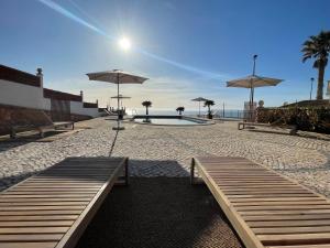a pool with benches and umbrellas on a beach at The Ocean / Ericeirahills in Carvoeira +69 photos