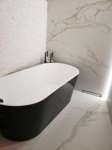 a white bath tub in a bathroom with marble walls at Red & Yellow Old Town in Lviv