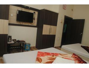 Pokój z dwoma łóżkami i telewizorem na ścianie w obiekcie HOTEL MADHUVAN, Madhavpur w mieście Mādhavpur
