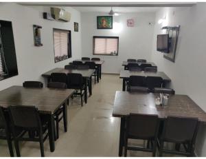 ein Restaurant mit Holztischen und -stühlen in einem Zimmer in der Unterkunft HOTEL MADHUVAN, Madhavpur in Mādhavpur