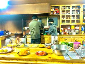 two men standing in a kitchen preparing food at Hotel Waterfall in Phakding
