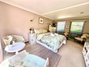 1 dormitorio con 1 cama, 1 silla y 1 mesa en French Provincial The Garden Suite at Chapmans incl Breakfast & Golf en Moss Vale