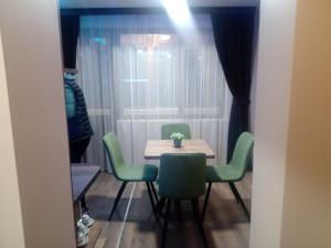 mesa y sillas en una habitación con ventana en Кръчмъ При Байката апарт, en Teteven