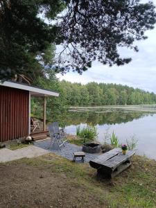 Old Finnish lakeside cottage with sauna في أولو: كابينة فيها طاولة ومقعد بجانب البحيرة