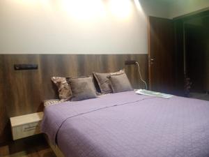 1 dormitorio con 1 cama con manta morada en Кръчмъ При Байката апарт, en Teteven