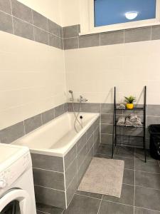 a bathroom with a tub and a washing machine at Amazing large 2,5rooms with terrace and parking! in Bratislava