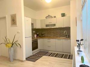 a kitchen with white cabinets and a vase with a plant at Amazing large 2,5rooms with terrace and parking! in Bratislava