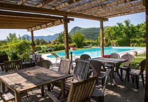 un patio con tavoli, sedie e piscina di AGRITURISMO B&B BIO LA TANA DEL LELE a Serra San Quirico