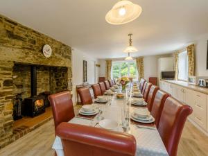 a dining room with a long table with chairs and a fireplace at 8 Bed in Clovelly 85428 in Woolfardisworthy