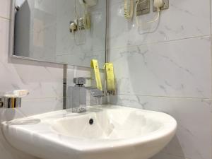 y baño con lavabo blanco y espejo. en Landmark Hotel Suites, en Tabuk
