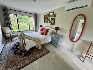 a bedroom with a bed and a mirror and a chair at The Aloe Garden Cottage in Howick