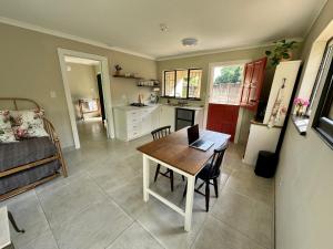 a kitchen and dining room with a table and chairs at The Aloe Garden Cottage in Howick
