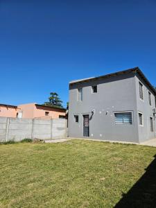 a large white house with a grass yard at Casa Muka in Tandil