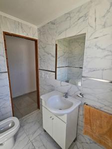 a white bathroom with a sink and a toilet at Casa Muka in Tandil