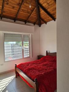 a bedroom with a red bed and a window at Casa Muka in Tandil