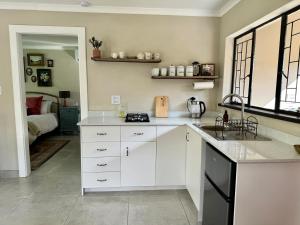 a kitchen with white cabinets and a sink at The Aloe Garden Cottage in Howick