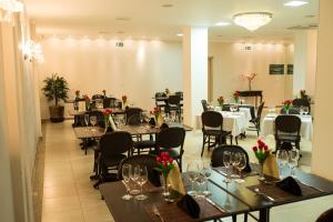 Francisco Beltrão Palace Hotel في فرانسيسكو بيلتراو: غرفة طعام مع طاولات وكراسي عليها زهور