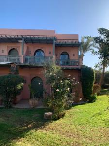 uma casa cor-de-rosa com uma varanda e um quintal em AbirKech appartement em Marrakech