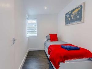 a small bedroom with a red blanket on a bed at 3 Bed in Widemouth Bay 86151 in Marhamchurch