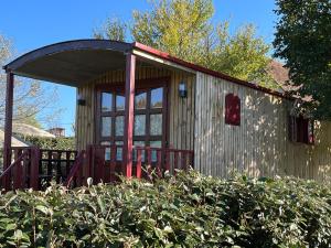 un petit hangar avec une porte rouge dans un jardin dans l'établissement Ushuaïa Villages La Buissonnière Lodges, à Chisseaux