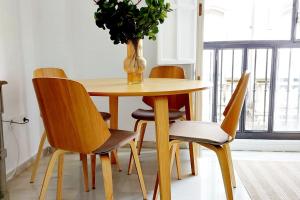 a dining room table with chairs and a vase with a plant at Apartamento Azahar Alfonso XII in Seville