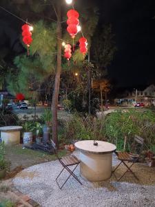 a table and two chairs and a tree with lanterns at Leisure Corner 17 茶馆民宿 in Bukit Mertajam
