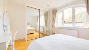 ein weißes Schlafzimmer mit einem Spiegel und einem Bett in der Unterkunft Notting Hill Luxury Duplex in London