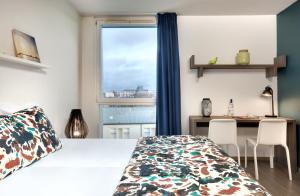a bedroom with a bed and a desk and a window at Ténéo Apparthôtel Bordeaux Maritime - Cité du vin in Bordeaux