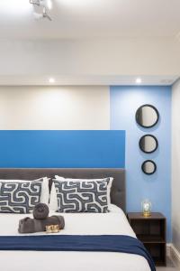 a bedroom with a bed with a blue accent wall at Madison Modern Oasis in Cape Town