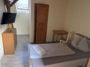 a bedroom with a bed and a television and a door at Zimmervermietung Graupner in Rossau