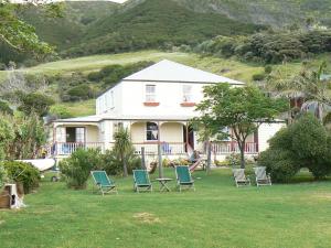 a house with chairs on the lawn in front of it at Endless Summer Lodge in Ahipara
