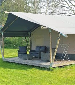 um gazebo com sofás e cadeiras num campo em Camping de Peelweide em Grashoek